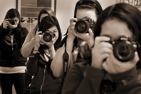 Five students with camera lenses pointing at the photographer