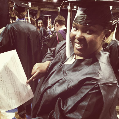 A student in cap and gown points to his name in the commencement program