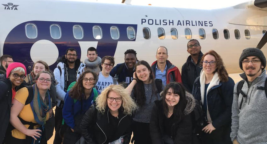 Students pose in front of a plane after landing in Poland for an international reporting course.