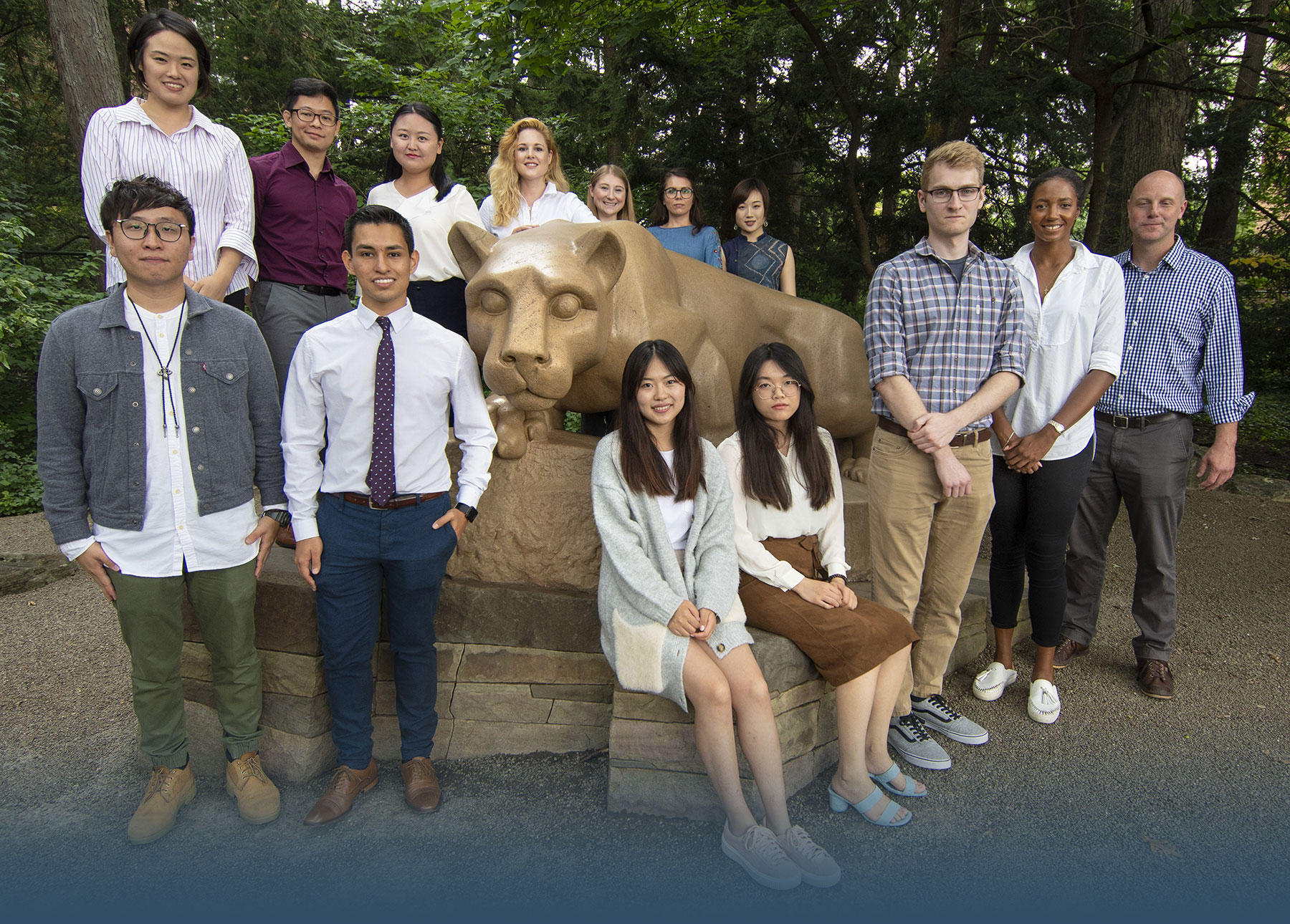 A group of graduate students posing at the Nittany Lion Shrine.