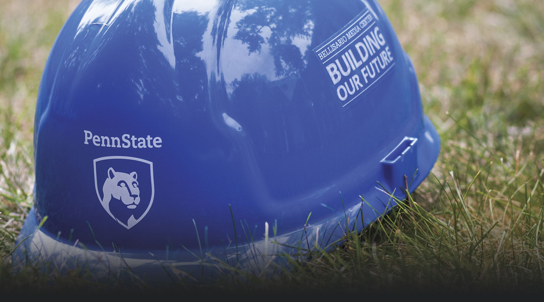 A blue hardhat with the Penn State logo features text on the side that reads Bellisario Media Center - Building Our Future