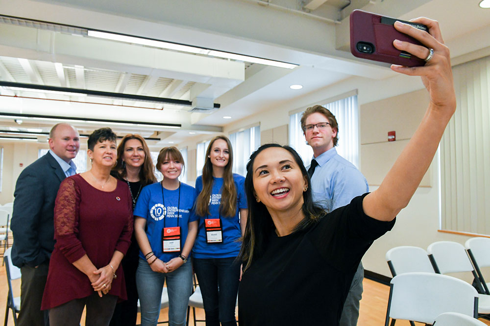 Guest speaker photographs a selfie with College students behind her