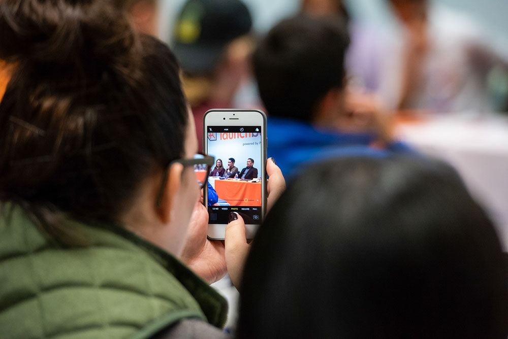 Meta photograph of a student taking a photograph on her phone at a LaunchBox event