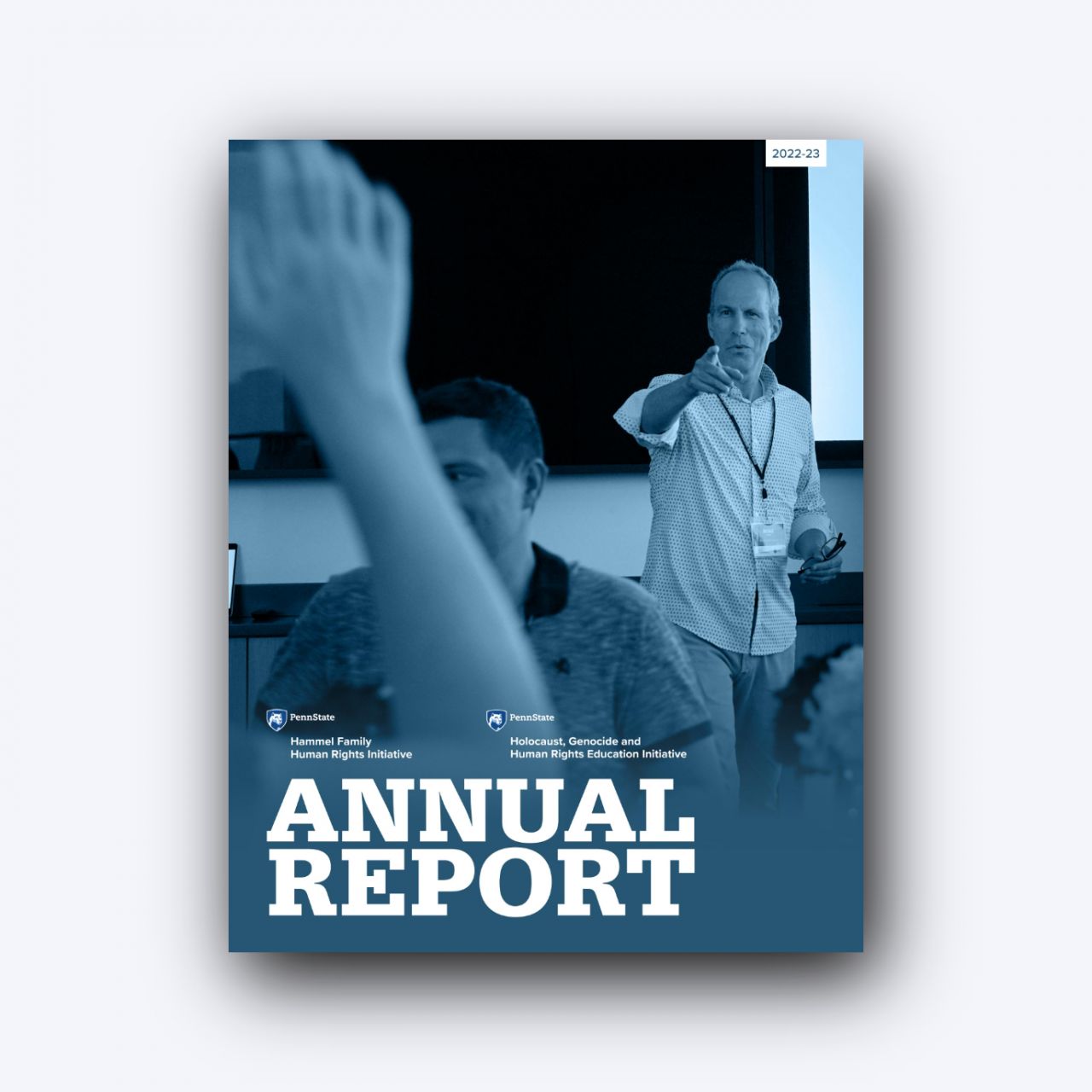 Man speaking to audience behind a blurred raised hand. In the bottom left corner, two marks above text "Annual Report"