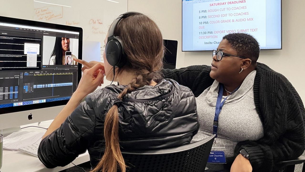 Mentor assisting student in front of computer editing program.