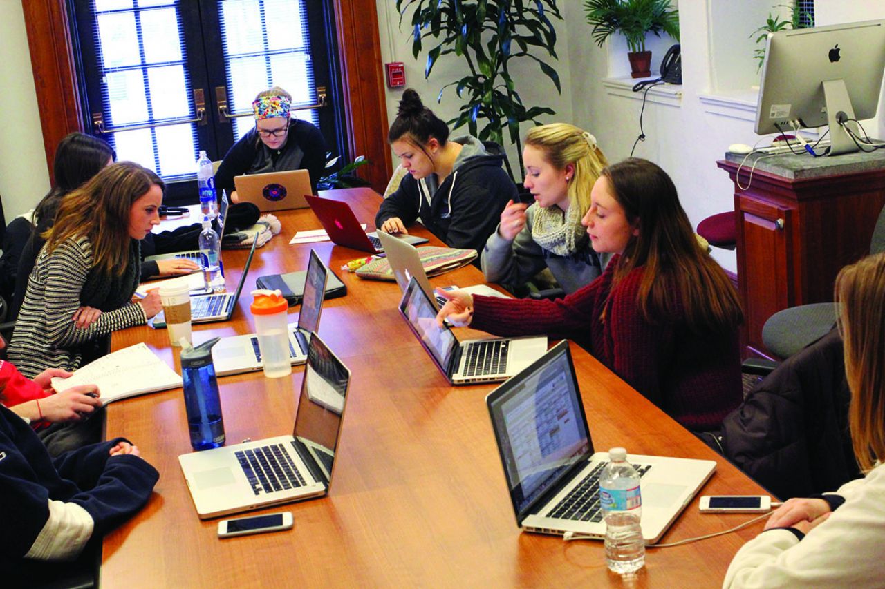 Students working at a table on their laptops