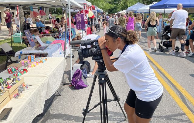 A student focuses her camera on a table of items for sale.