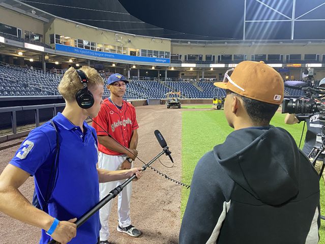 Two students with boom mic and baseball player.