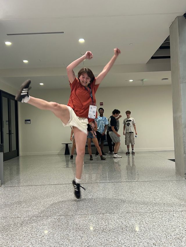 A student leaps in hallway.