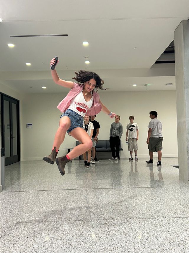 A student leaps in hallway.