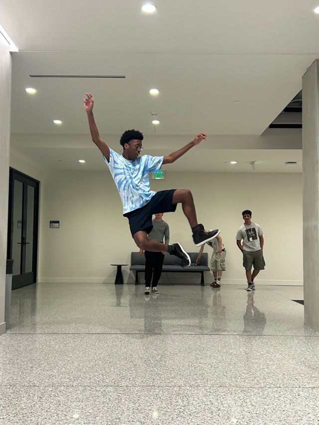 A student leaps in hallway.