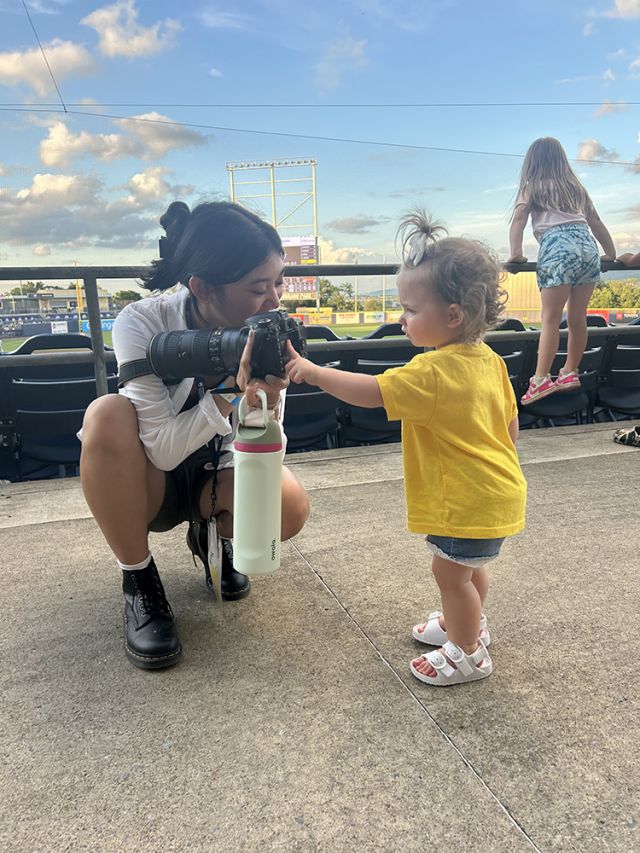 Kneeling student showing camera to toddler