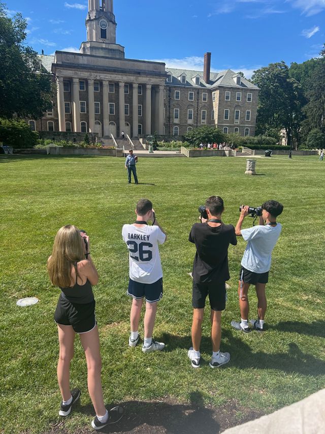 Four students shooting on Old Main lawn.