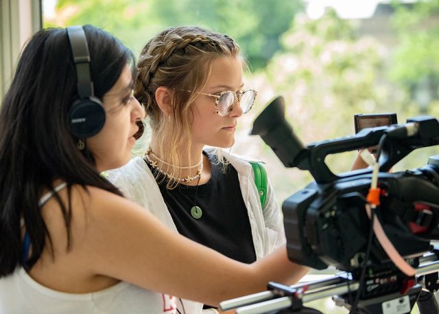 Two students collaborate to set up a camera shot.