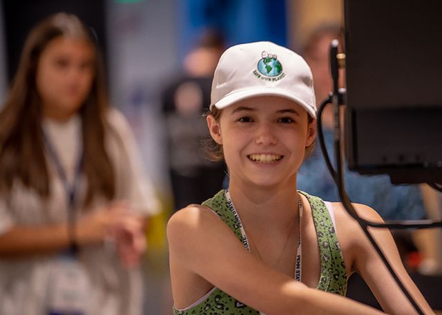 A student in a hat smiles at the camers.