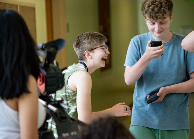 Students laugh while discussing a camera shot.