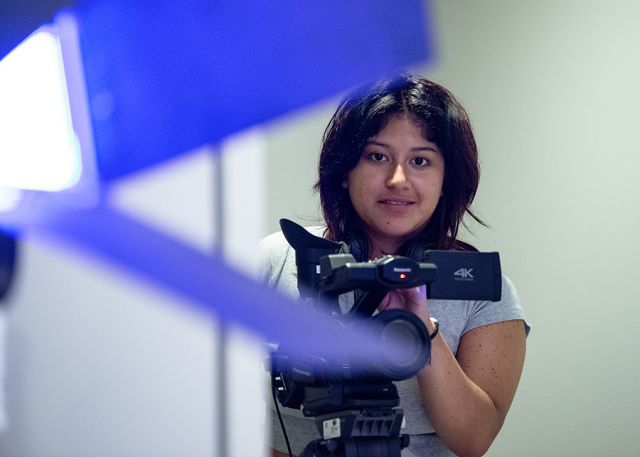 A student looks at the camera, framed by parts of a camera.