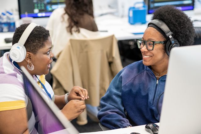 An instructor and student share a smile while editing video.