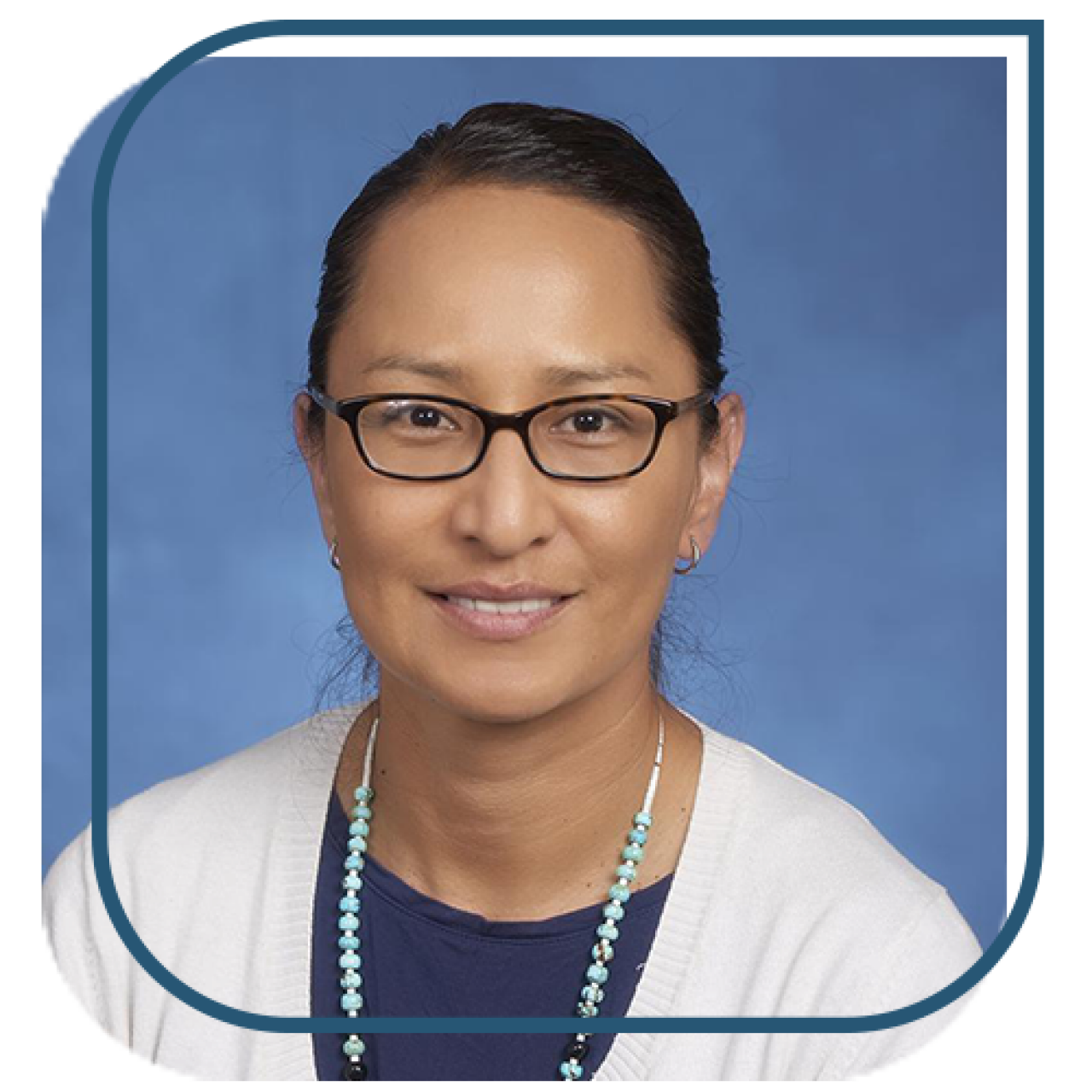 a woman wearing glasses, a white sweater, and dark blue shirt smiles in front of a blue background