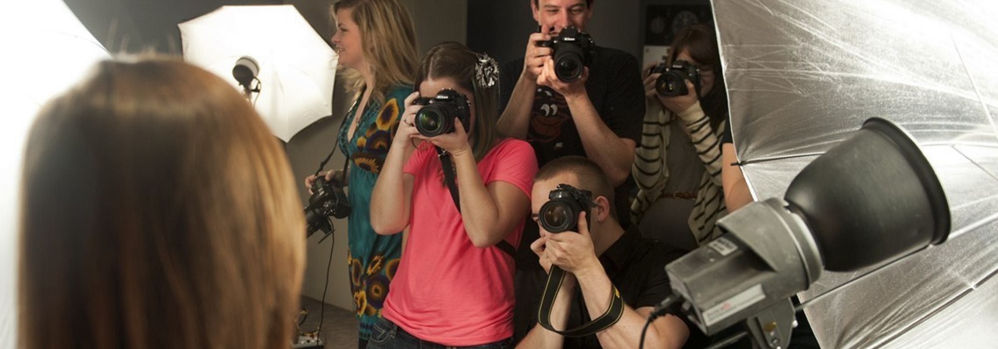 Five students are pointing cameras towards a model in the foreground with lights and reflectors all around.