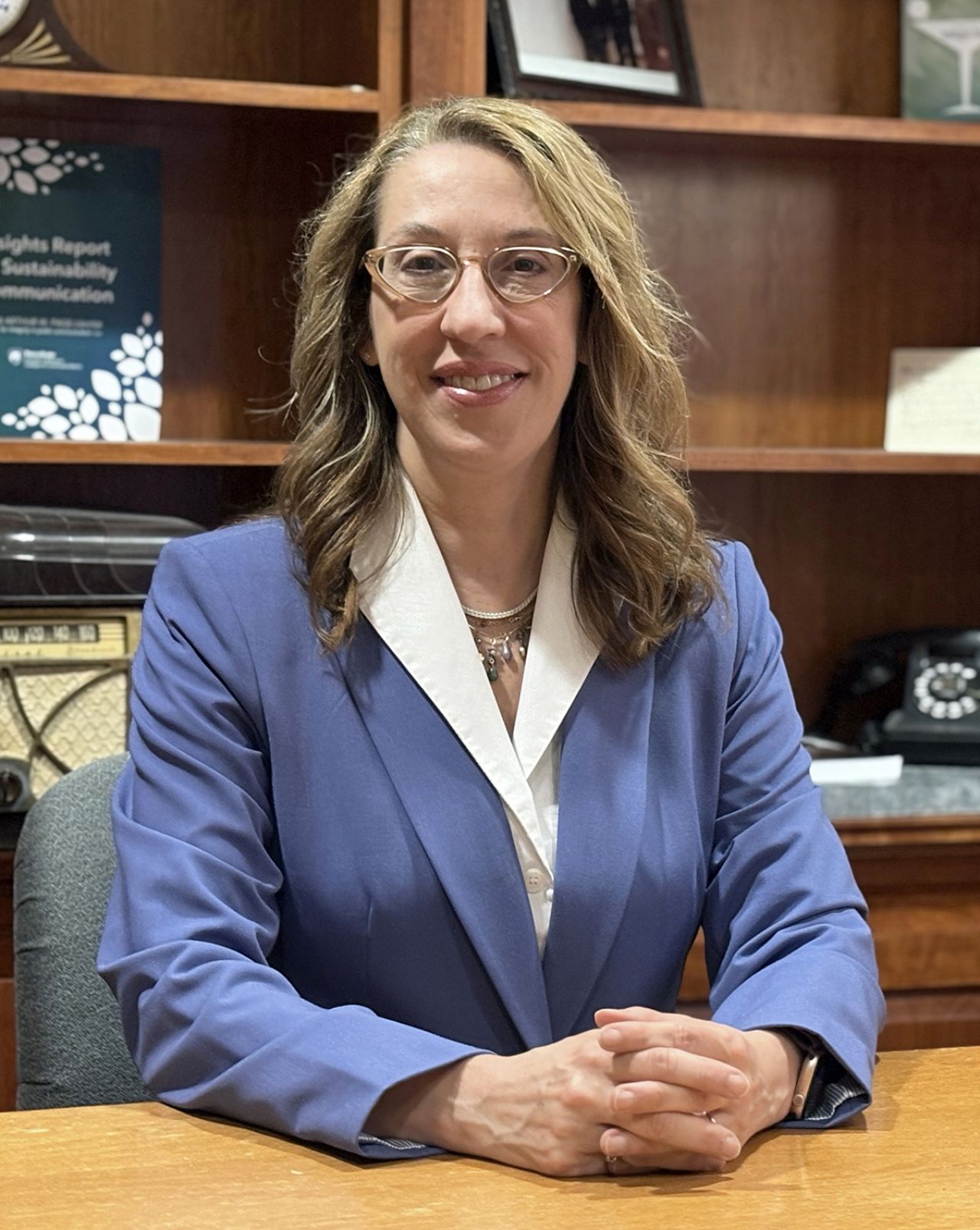 Interim Dean Denise, a woman with shoulder-length brown hair wearing a blue pant suit, seated.