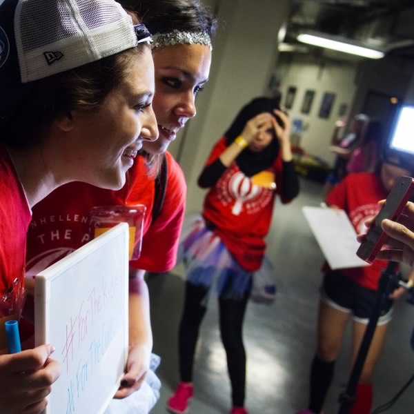 Students filming for a THON project stand in front of a whiteboard with hashtag ForTheKids