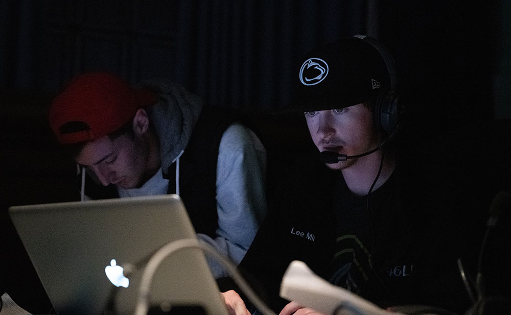 Two students behind a laptop and other streaming equipment during a live presentation.