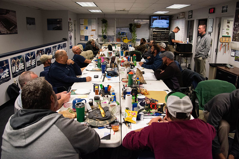 The groundskeeping crew all settled around some tables for a meeting.