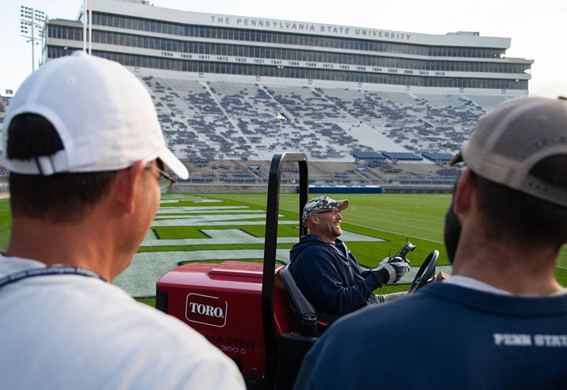 Several groundskeepers share a laugh on the field at Beaver Stadium.