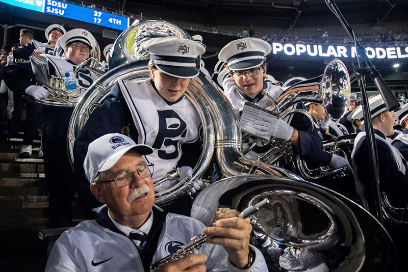 Dave Cree examines a broken flute while members of the brass section look over his shoulder.