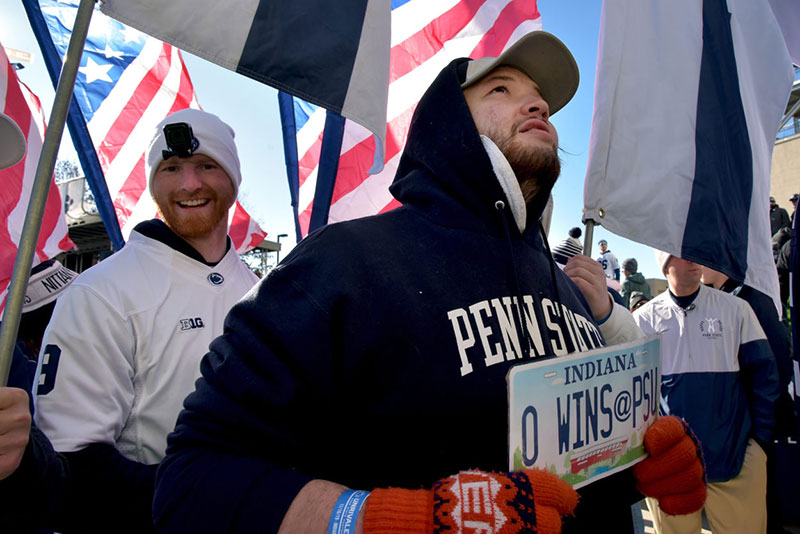 A fan in a blue Penn State hooded sweatshirt holds an Indiana license plate that reads zero wins at PSU