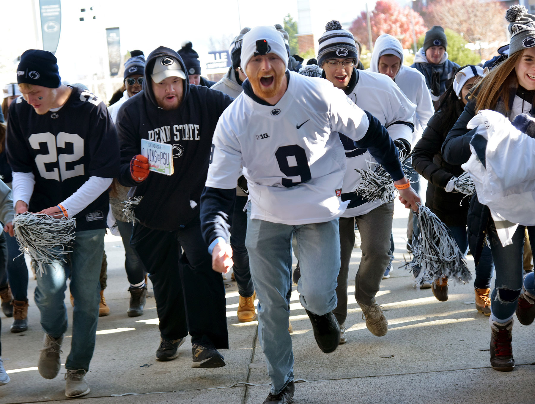 A crowd of fans dressed in Penn State gear running into the stadium to get the best seats in the student section.