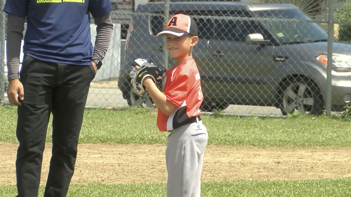 A young little league baseball player from Puerto Rico smiles as he readies to throw a ball