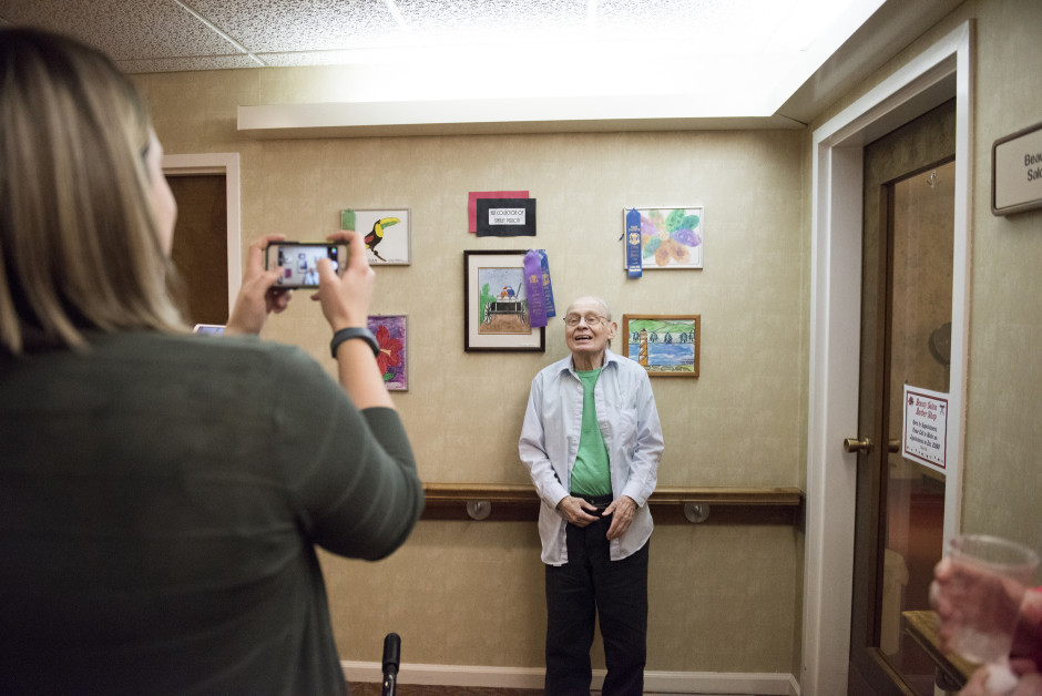 Stanley poses in front of some of his watercolor paintings.