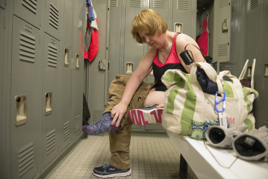 Cindy Kane in a YMCA locker room removing a shoe to get dressed for swimming class.