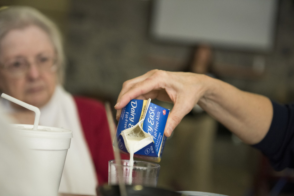 Lisa pours milk from a carton into a glass.