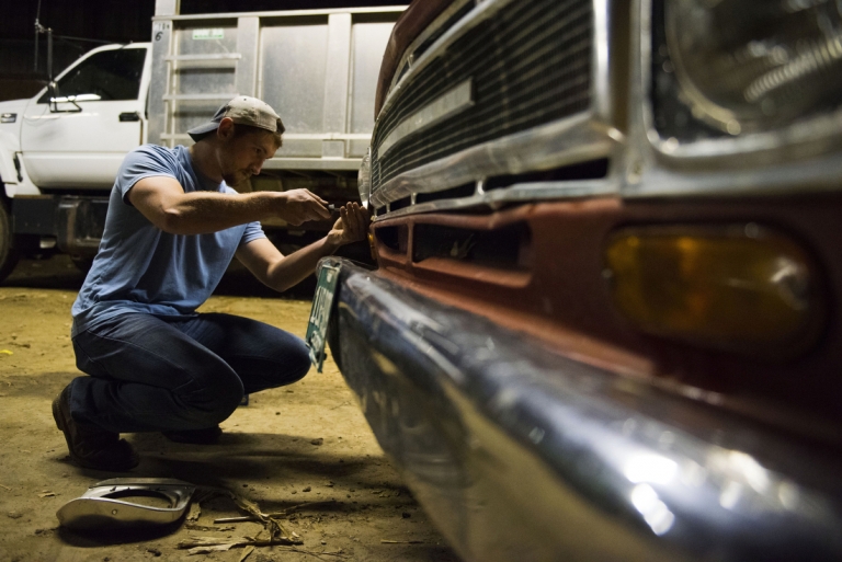 Zack undoing a screw to replace a headlight on a 1968 International picku up truck