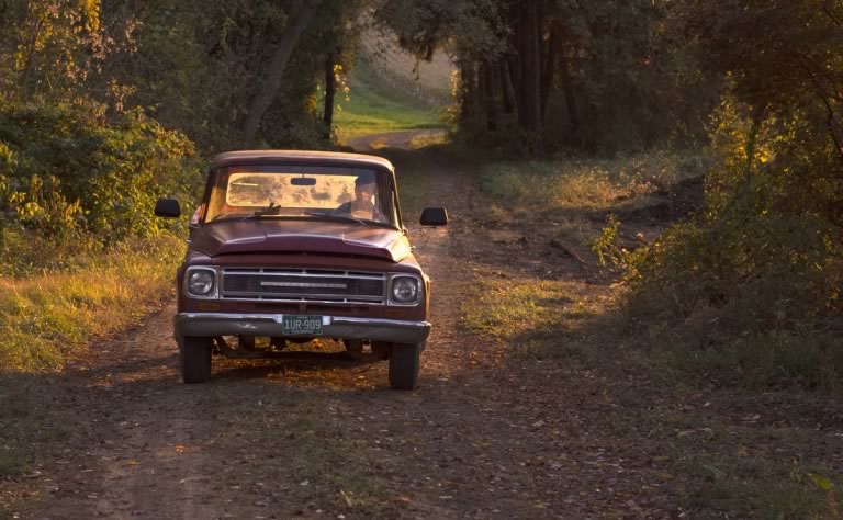 Zack driving his pickup down a gravel road on the Meyer Dairy farm