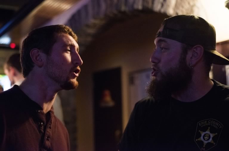 Zack and his friend Paul look at each other while singing along to live music.