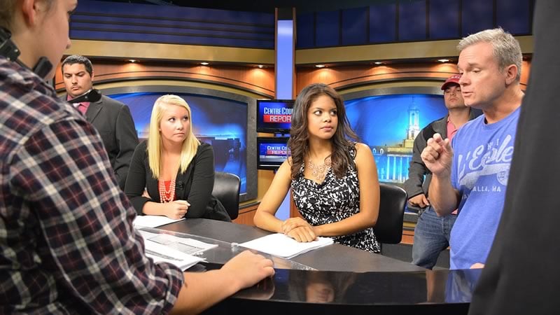 Students discuss the upcoming broadcast on the set of the Center County Report.